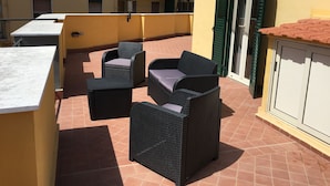 A terrace with wicker furniture, a tiled floor, and a yellow building with balconies. - VILLA ROSA - Apartment n. 5 "MYRTLE" (2 beds): (Napoli)