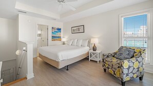 A bedroom with a bed, a chair, a ceiling fan, a window with blinds, and a painting on the wall. - Sundancer, East. Beachfront 5BR Pool! PERFECT location. 😎 (Gulf Shores)