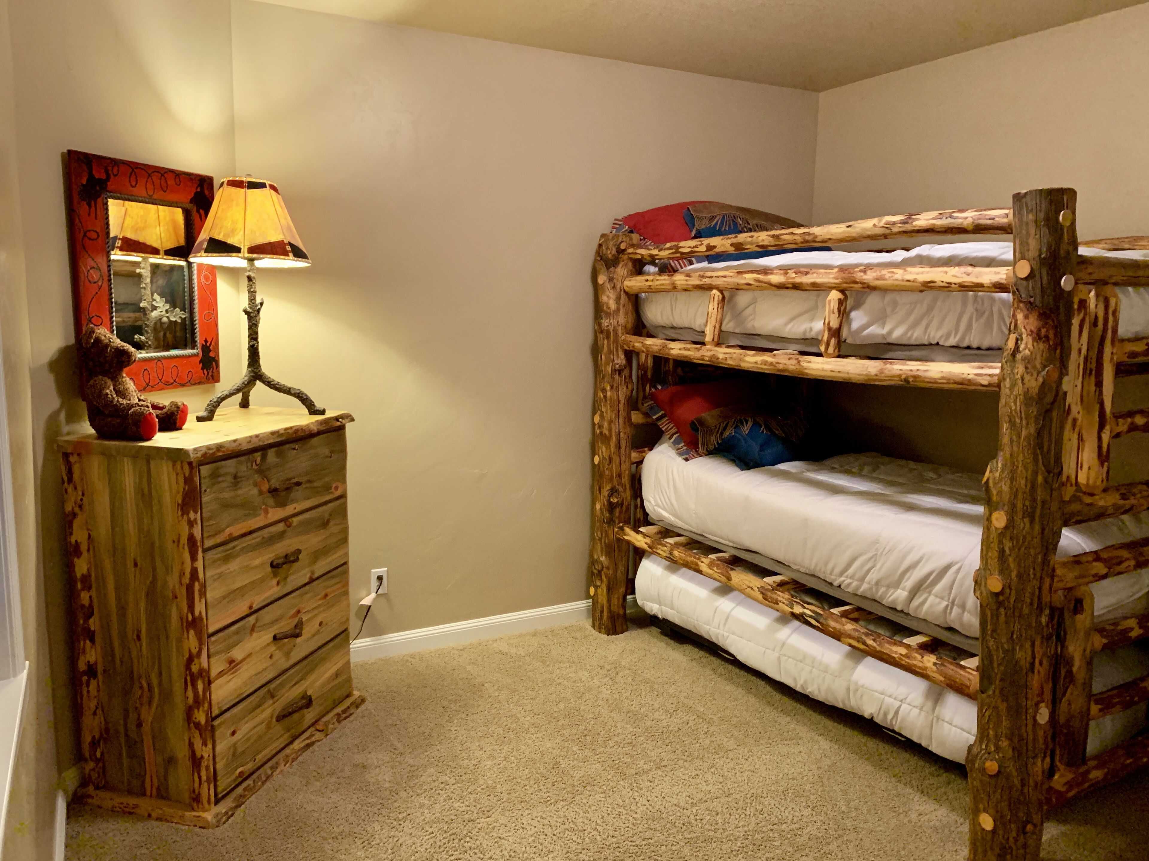 Una cama litera con estructura de madera y un aparador con cajones.