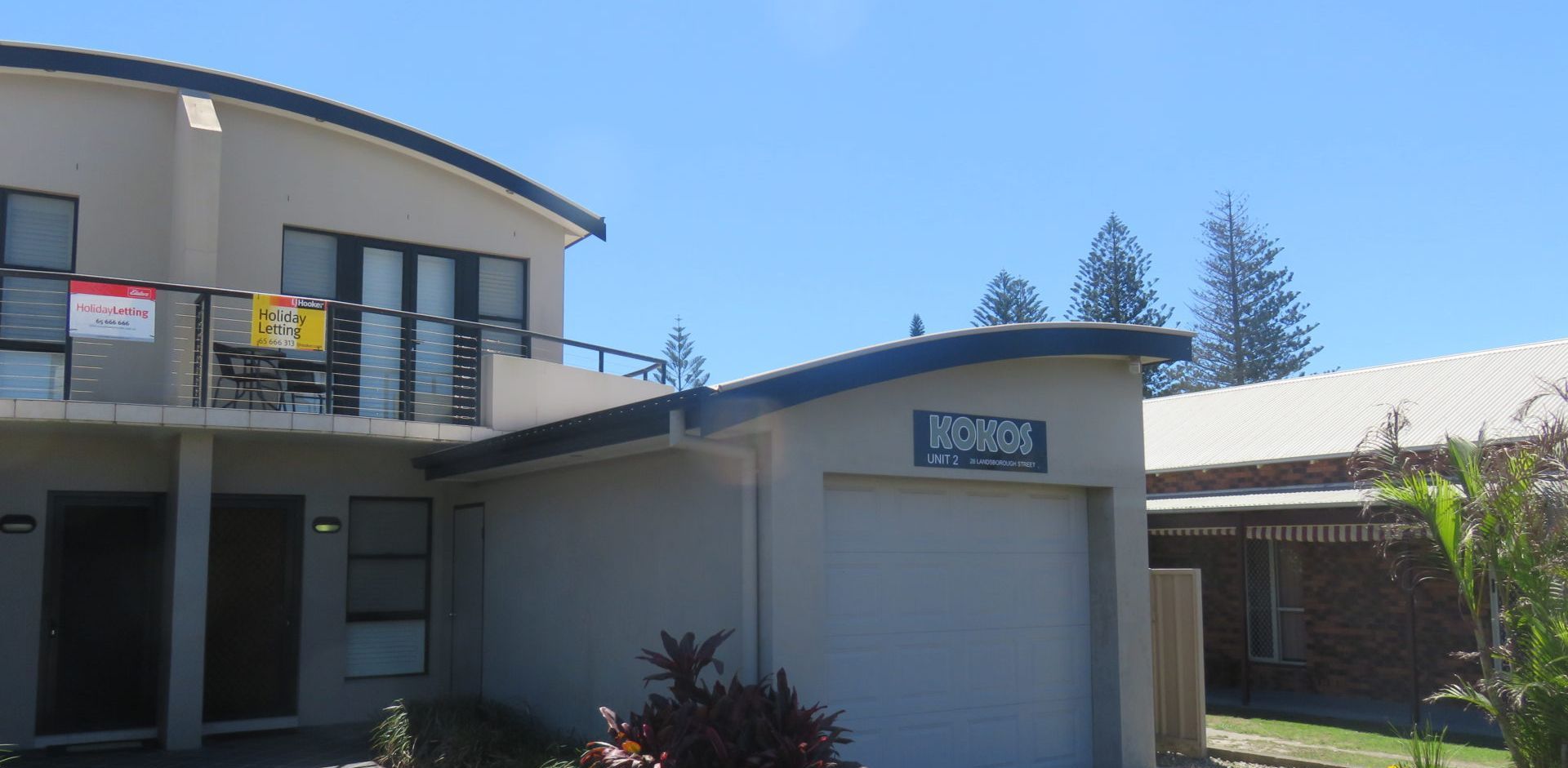 A two-story building with a sign for 'Holiday Letting' and 'HOKOS UNIT 2' on the ground floor.