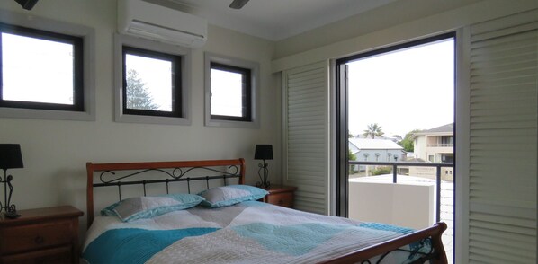 A bedroom with a bed, two bedside tables with lamps, a window, and a view of the outside. - KOKO'S - THREE BEDROOMS, SPA BATH, MODERN (South West Rocks)