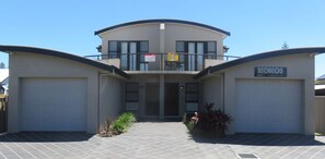 A modern two-story house with a garage on each side, a balcony on the upper floor, and a sign indicating 'Holiday Letting'. - KOKO'S - THREE BEDROOMS, SPA BATH, MODERN (South West Rocks)