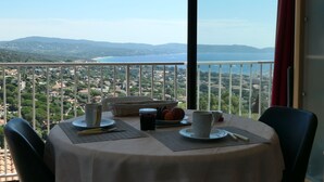 A table set for two with a view of a coastal landscape. - Panoramic sea view, swimming pool, garden. 
Quiet & comfortable, refurbished  (Cavalaire-sur-Mer)