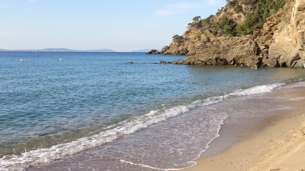 A coastal beach with clear blue water, sandy shore, and rocky cliffs. - Panoramic sea view, swimming pool, garden. 
Quiet & comfortable, refurbished  (Cavalaire-sur-Mer)