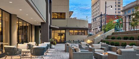 An outdoor patio with wicker furniture and a fire feature.