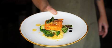 Une personne tenant une assiette contenant des aliments, notamment des brocolis et un morceau de saumon.