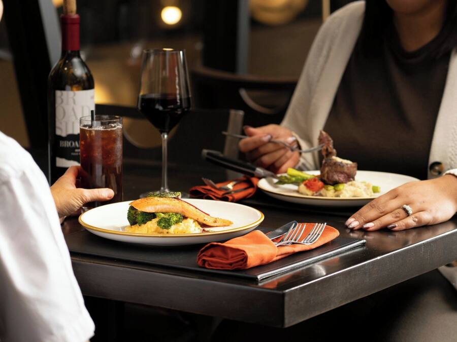 A dining table with plates of food, a bottle of wine, and glasses.