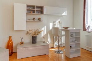 A modern, minimalist living room with a white cabinet, a white chair, and a wooden floor.