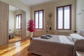 A bedroom with a large bed, a mirror, a radiator, and a window with curtains.