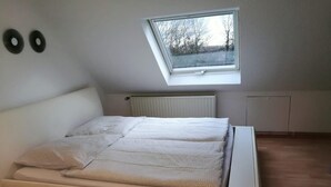 A bedroom with a skylight, a bed, a radiator, and a window. - Vacation apartment Harmonie 45 m2 (Solingen)