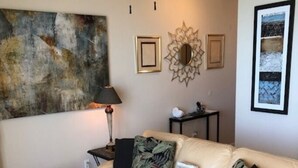 Een woonkamer met een beige bank, een glazen salontafel en decoratieve kussens.