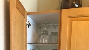 Een keuken met houten kastjes, een witte koelkast en planken met glazen potten en verpakkingen.