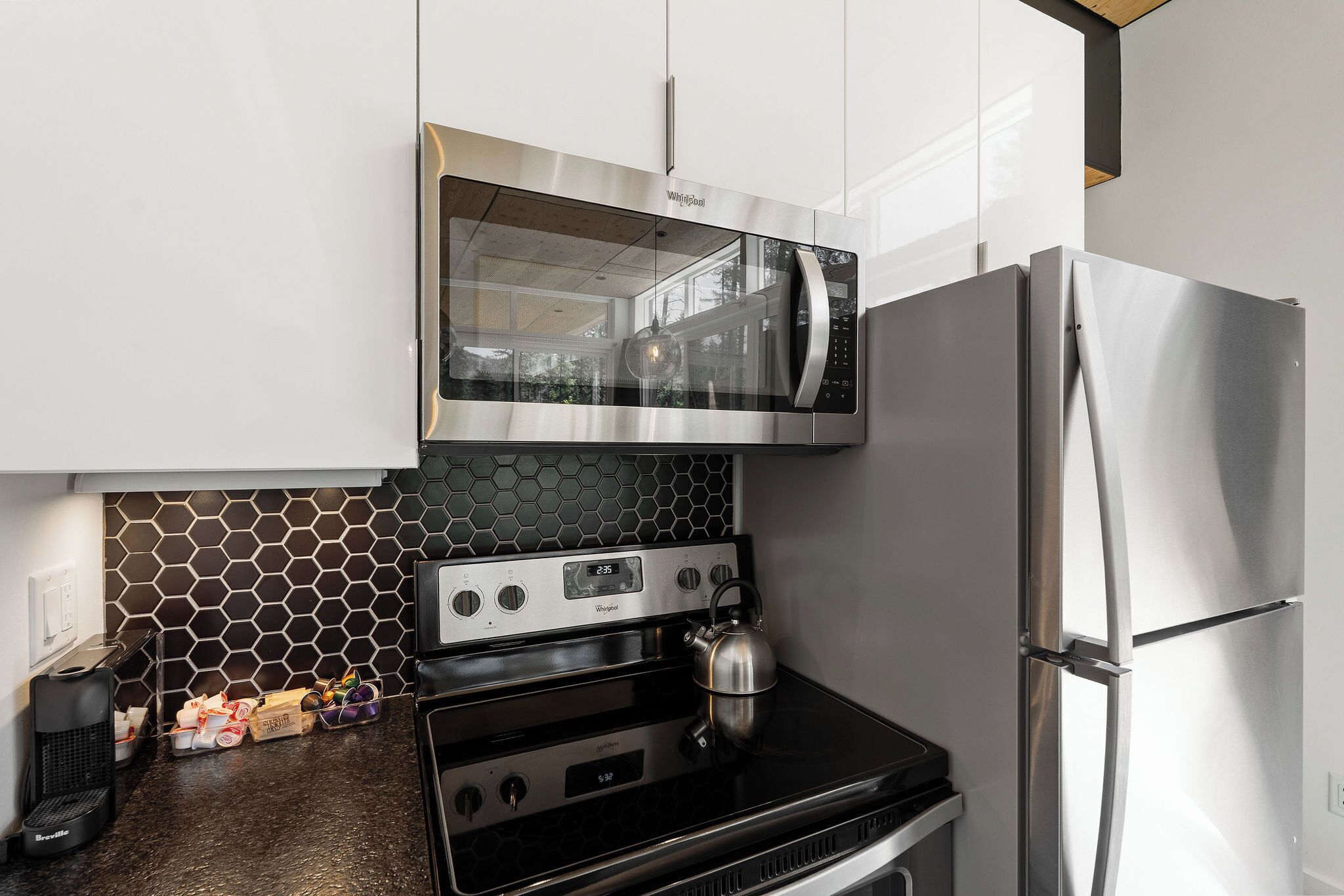 A kitchen with a stainless steel microwave, oven, and refrigerator.