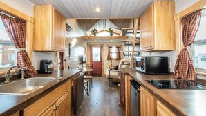 Una cocina compacta con armarios de madera, un microondas, un lavabo y un pequeño comedor.