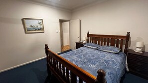 A bedroom with a wooden bed, a nightstand, a lamp, and a painting on the wall.