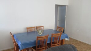 En spiseplads med et bord dækket af en blå dug, omgivet af træstole.