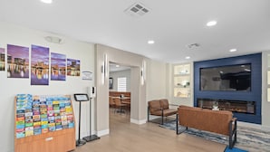A modern hotel lobby with a seating area, a fireplace, and a display of local attractions. - Baymont by Wyndham Orlando Downtown (Orlando)