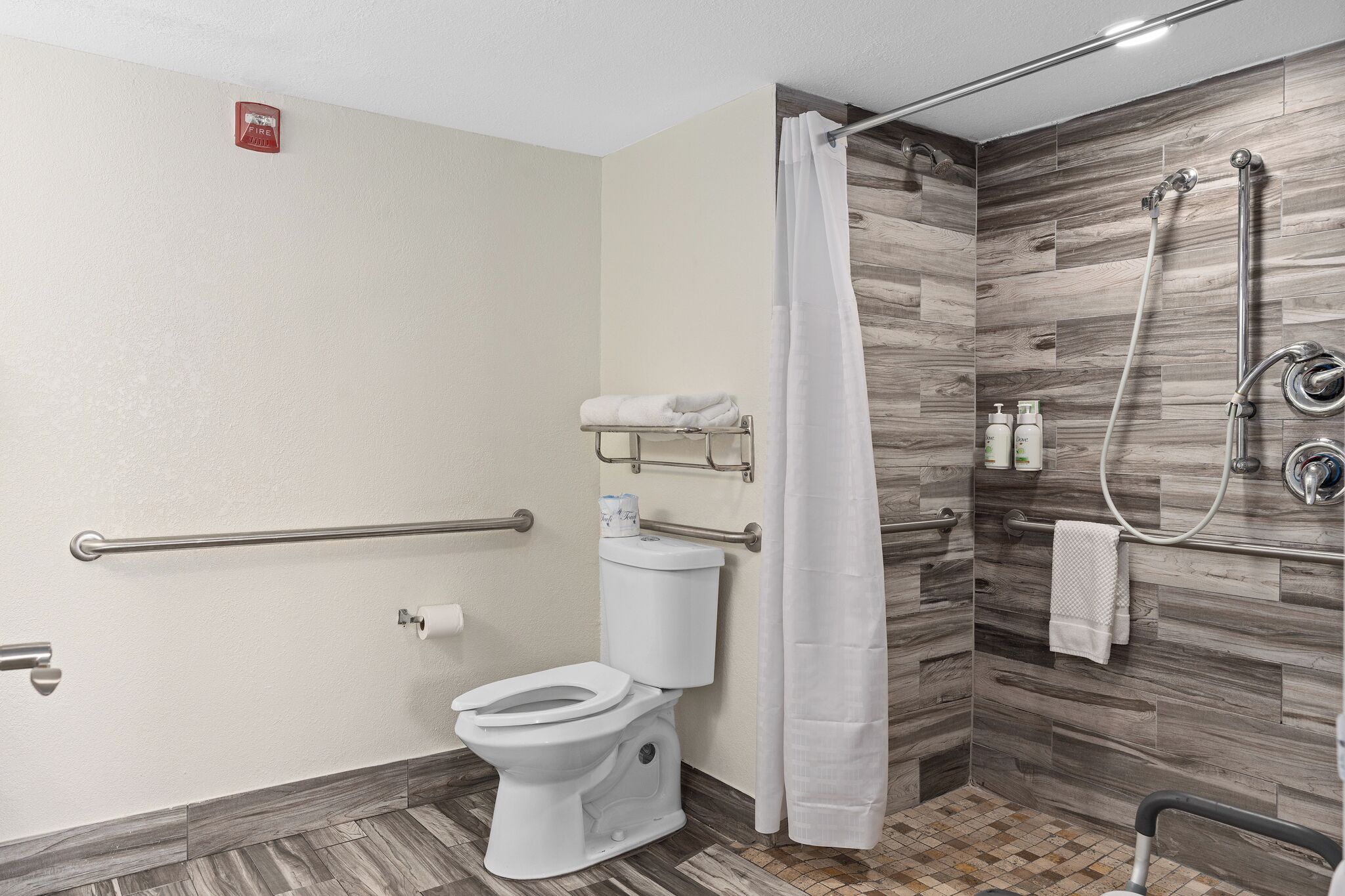 A modern bathroom with a toilet, shower, and grab bars.
