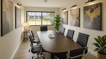A conference room with a long table, black leather chairs, and framed artwork on the walls.
