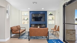 A modern lobby with a blue accent wall, a fireplace, leather sofas, and a reception desk. - Baymont by Wyndham Orlando Downtown (Orlando)