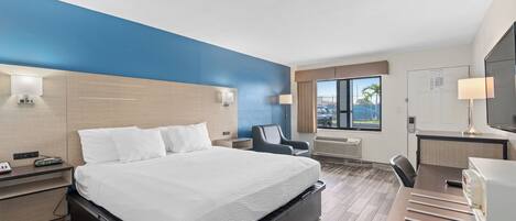 Habitación de hotel con cama, escritorio, silla y vistas al exterior.