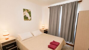 Et hotelværelse med en seng, to sengeborde, et klædeskab og et maleri på væggen.