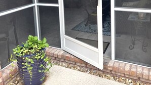 En indhegnet terrasse med en skydedør, en plantekasse og en murstensvæg.