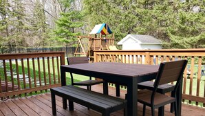 A wooden deck with a table and chairs, a swing set, and a small shed. - Perfect Family Getaway!  (Union Pier)