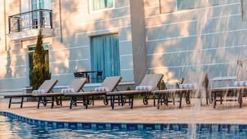 Una piscina al aire libre, sillones reclinables de piscina