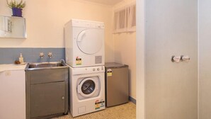 Uma lavanderia compacta com máquina de lavar, secadora e uma pia pequena.