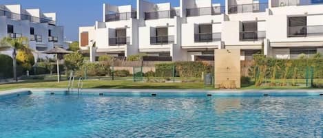 A modern residential building with a swimming pool in front.