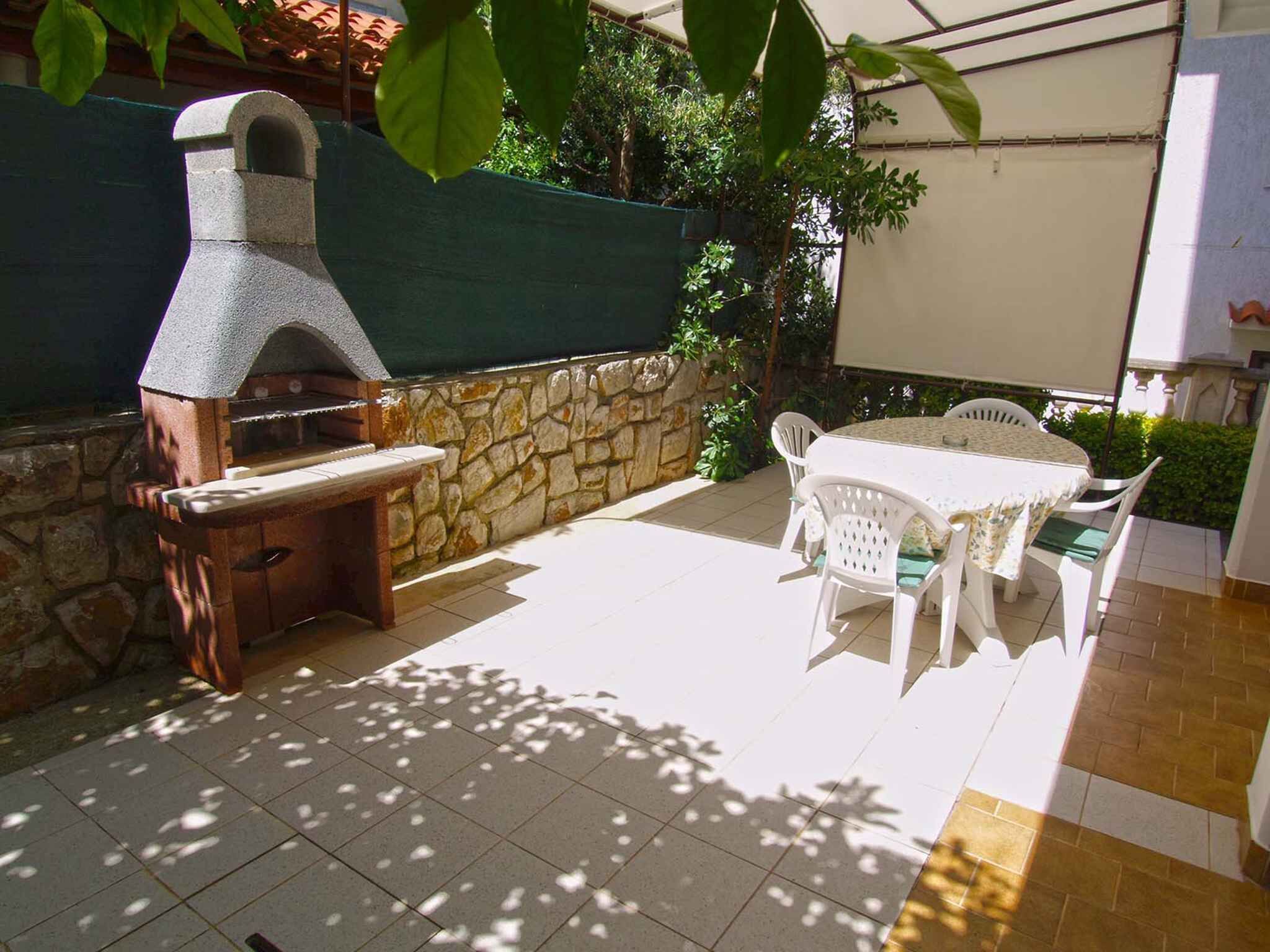 Eine Außenpatio mit einer Steinmauer, einem Pizzaofen und einem Tisch mit Stühlen.