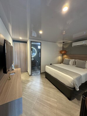 A modern hotel room with a bed, a TV, a desk, and an air conditioning unit. - Molino De Viento (San Andrés)