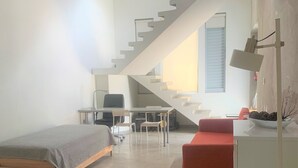 A modern room with a bed, a desk, a red sofa, and a staircase leading to an upper level. - Zen Retreat (San Juan)