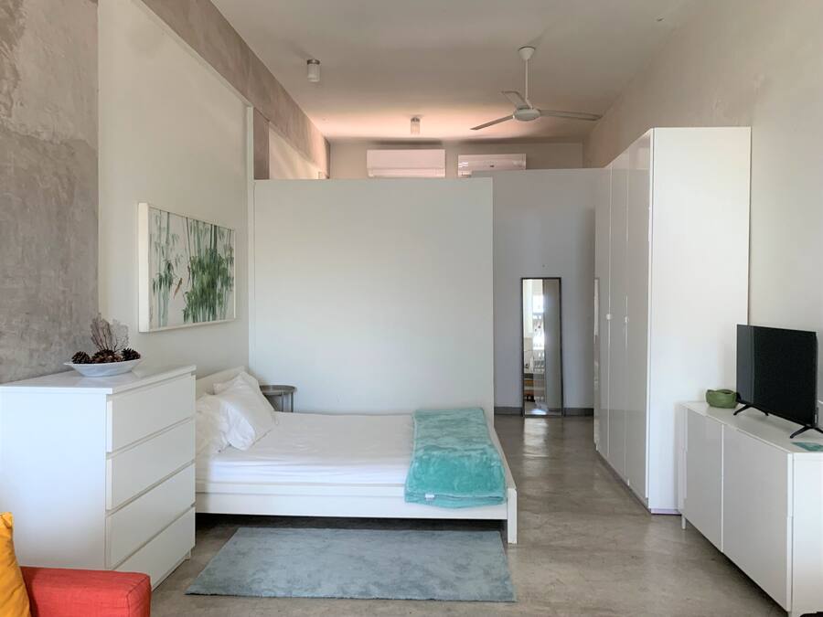 A modern bedroom with a bed, a nightstand, a dresser, a TV, and a painting on the wall.