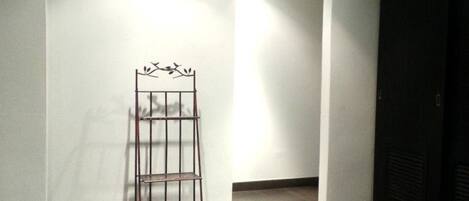 A hallway with a metal rack, white walls, and wooden flooring.