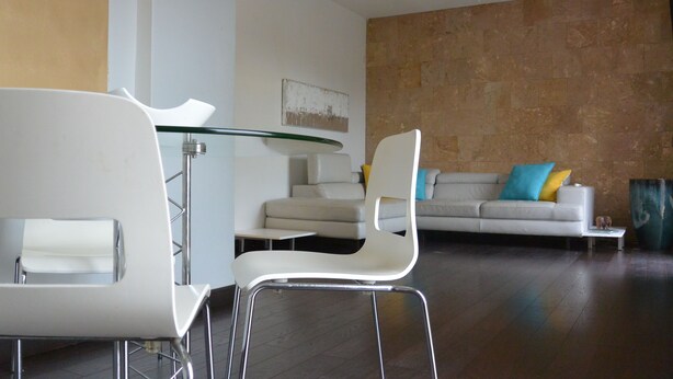 A modern living room with a glass-top dining table, white chairs, a sofa with colorful cushions, and a textured wall. - Zen Retreat (San Juan)
