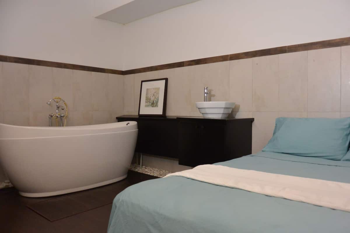 A bathroom with a bathtub, a sink, and a framed picture on the wall.