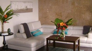 A modern living room with a white sofa, a coffee table, and a stone accent wall. - Zen Retreat (San Juan)