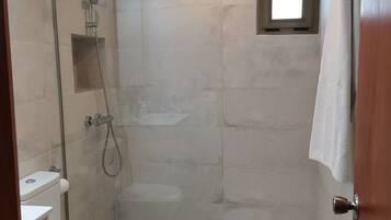 Een bad/douchecombinatie, een haardroger, handdoeken, toiletpapier
