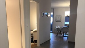 Un hall d’entrée spacieux, doté d’un plancher en bois, mène à une salle à manger équipée d’une table et de chaises.