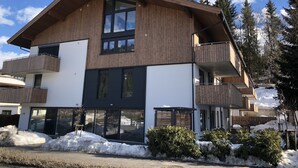 Un bâtiment moderne à deux étages, doté d’un revêtement en bois, de grandes fenêtres et de balcons.