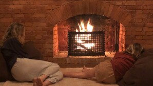 Two people sitting on a rug in front of a brick fireplace with a fire burning. - Full board on an organic tea estate high in the hills - whole cottage with staff (Hildummulla)