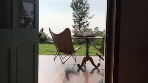 An open door leading to an outdoor patio with a table and a chair. - Full board on an organic tea estate high in the hills - whole cottage with staff (Hildummulla)