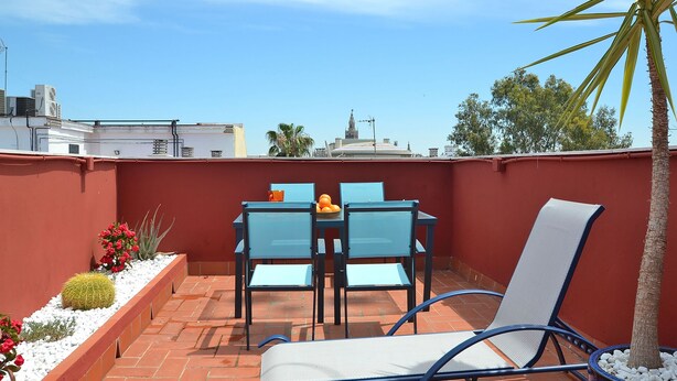 A rooftop patio with a table and chairs, a small plant, and a view of a building with a dome in the distance. - Triana Terrace. 1-bedroom, roof-top terrace (Sevilla)