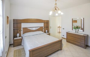 A bedroom with a wooden bed, bedside tables, a dresser, a mirror, and a chandelier. - Lovely home in Camaiore (Camaiore)