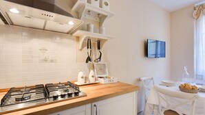 Una cocina moderna con estufa a gas, armarios blancos y un comedor con mesa para dos.