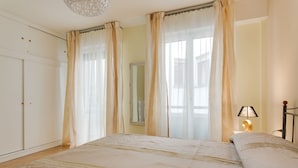 Un dormitorio con cama, cortinas, mesita de noche y lámpara.