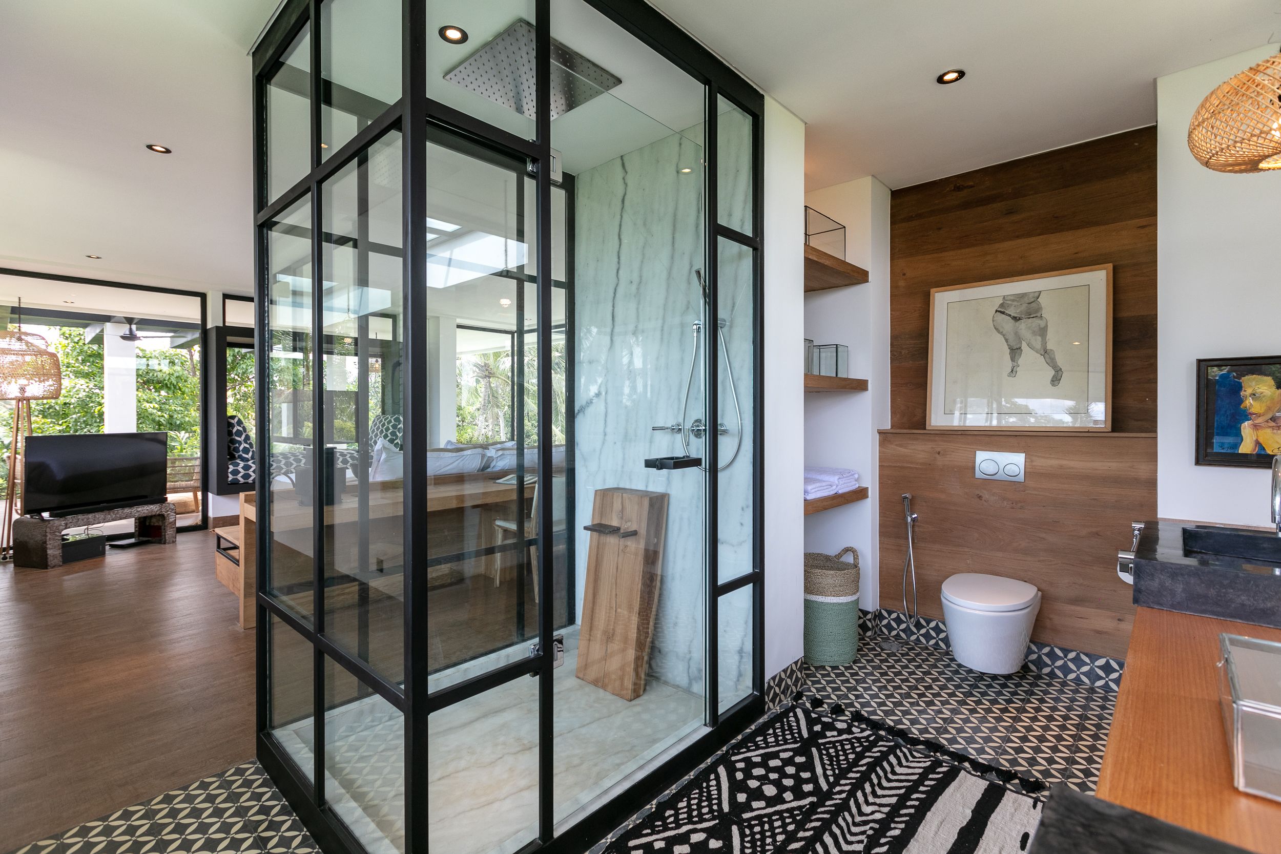Um banheiro moderno com box de vidro, um banco de madeira e vaso sanitário.