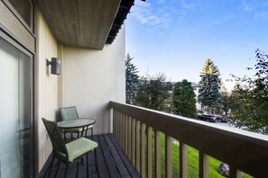 Un balcon avec une table et des chaises, une vue sur la rue et un immeuble en arrière-plan.